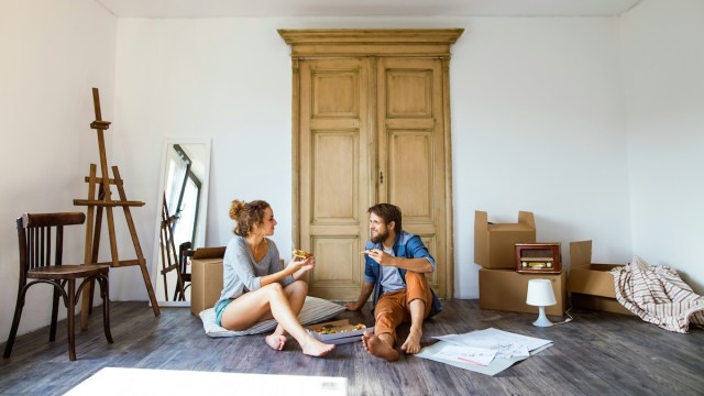 Moving abroad checklist represented by two people eating pizza in a nearly empty apartment.