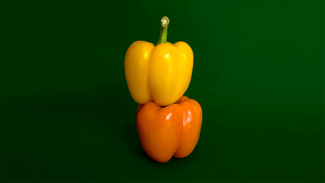 one yellow and orange pepper stacked on top of each other with a green background demonstrating Most Common Adjectives In Spanish