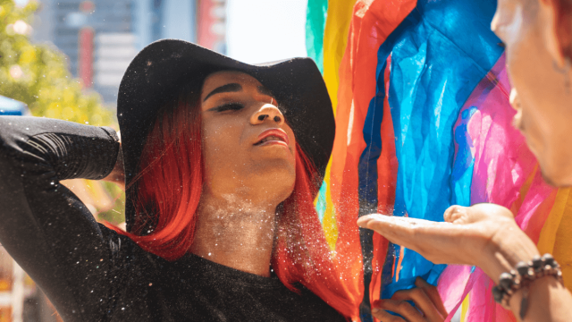 pride parade goer tilting head back while someone blows glitter drag slang aave words