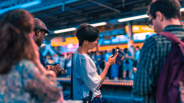A person looking at their phone on the subway tracks and learning about gender-neutral pronouns