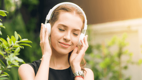 A woman with headphones on listening to German Podcasts
