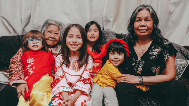 Types of family represented by three generations of a family sitting together, looking at the camera.