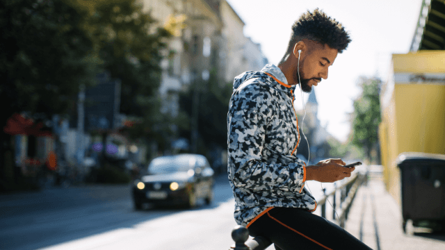 A man leaning on a pole outside while listening to Norwegian podcasts