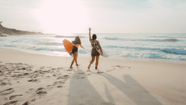 Summer words represented by an image of friends walking at the beach on a sunny day.