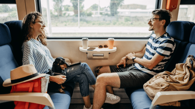 Speak the local language represented by a man and a woman sitting opposite one another on a train that is traveling through Europe